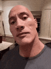 a bald man in a grey shirt is making a funny face .
