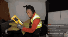 a man is holding a yellow nerf gun in front of a couch