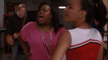 two cheerleaders are standing next to each other and one is wearing a pink shirt