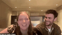 a man and a woman are smiling and laughing while sitting next to each other in a room .