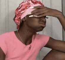 a woman wearing a pink hat and a pink shirt is covering her face .