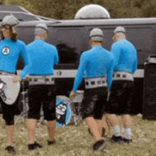 a group of men in blue shirts are standing in front of a van