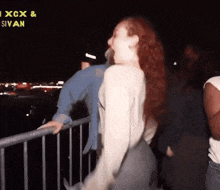 a woman with red hair is standing in front of a sign that says ixcx & sivan