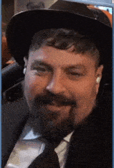 a man with a beard wearing a black hat and tie