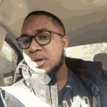 a man wearing glasses is sitting in the back seat of a car