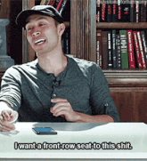 a man sitting at a table with the words i want a front row seat to this shit written below him