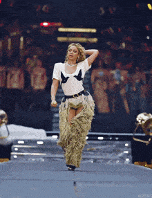 a woman in a white shirt and fringed pants is on a stage