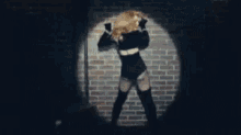 a woman is standing in front of a brick wall and dancing .