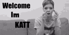 a black and white photo of a woman sitting on a couch with the words welcome im katt behind her .
