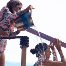 a woman pouring water from a bucket onto another woman