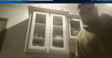 a blurry picture of a man standing in front of a cabinet with glass doors