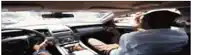 a man is sitting in the driver 's seat of a car talking on his phone .