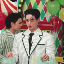 two men in suits and ties are standing next to each other in front of a carnival .
