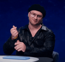 a man wearing glasses and a black hat is sitting at a table