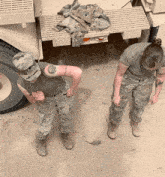 two soldiers are standing next to each other in front of a truck