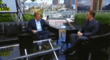 two men are sitting in front of a sign that says sss live