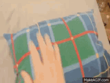 a dog is laying on a bed with a plaid blanket and a makeagif.com link