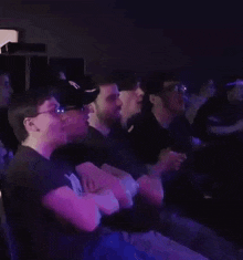 a group of people are sitting in a dark room clapping .