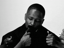 a black and white photo of a man lighting up a lighter