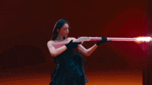 a woman in a black dress is holding a pink toy gun