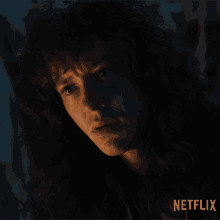 a close up of a woman 's face in the dark with a netflix logo in the corner .