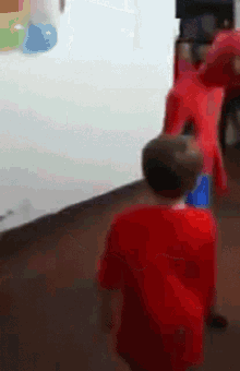 a boy in a red shirt is standing in front of a whiteboard