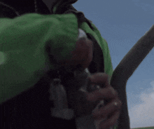 a person in a green jacket is holding a bottle of water