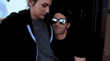 a man wearing sunglasses and a woman wearing a black hoodie