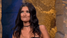 a woman in a black dress is standing in front of a gold statue and smiling .