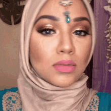 a close up of a woman wearing a hijab with a turquoise bead on her forehead