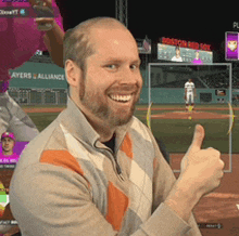 a man is smiling and giving a thumbs up in front of a boston red sox sign