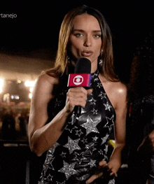 a woman holding a microphone with a red circle on it