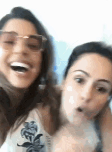 two women wearing sunglasses are making funny faces and laughing .