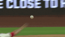 a baseball is being thrown in front of an advertisement that says close to home