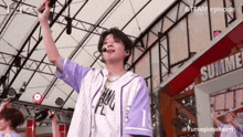 a young man singing into a microphone while wearing a purple and white shirt with the number 1 on it