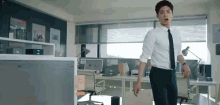 a man in a white shirt and black tie is standing in a room .