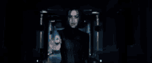 a woman is holding a gun in a dark room and pointing it at the camera .