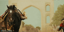 a man riding a horse in front of a building that says pranay and varma