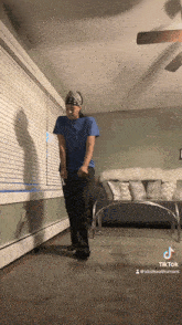 a person in a blue shirt is dancing in a living room with a ceiling fan in the background