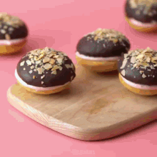 a wooden cutting board with four chocolate donuts on it