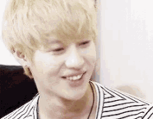 a close up of a young man wearing a striped shirt smiling .