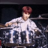 a man is playing drums on a stage in a dark room .