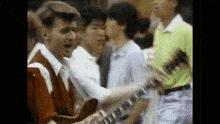 a man is playing a guitar in front of a group of people in a crowd .