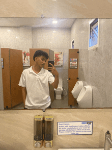 a man taking a selfie in a bathroom with a sign on the wall that says every drop