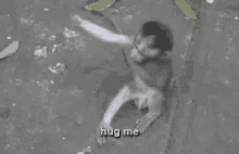 a black and white photo of a man laying on the ground with the words `` hug me '' written on the bottom .