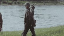 a group of soldiers are walking across a field near a river .