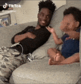 a man is sitting on a couch next to a baby who is sitting on the couch .