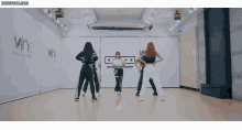 a group of girls are dancing in a room with a sign that says wne