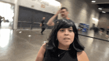 a woman in a black dress stands in a hallway