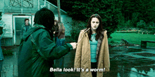 a woman says bella look it 's a worm in front of a man in a green jacket